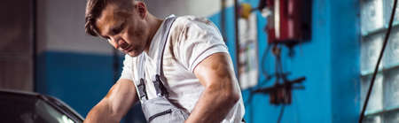 Young dirty car mechanic at work - panoramaの写真素材
