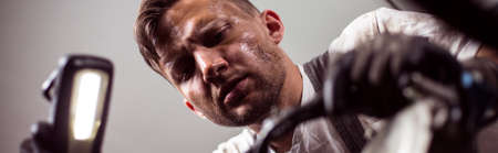 Close-up of male car mechanic holding flashlightの写真素材