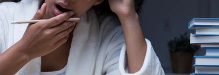 Panorama of sleepy and tired woman learning late at nightの写真素材