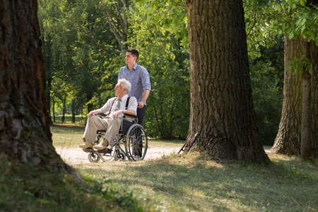 Photo of grandson enjoying sunny day with grandfather in parkの写真素材