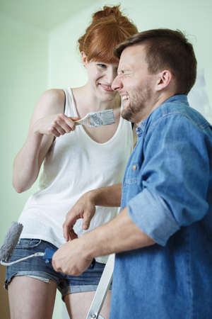 Happy couple redecorating house and painting wallsの写真素材