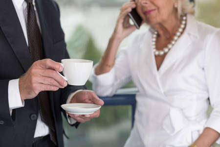 Elder businesswoman is busy even during breakの写真素材