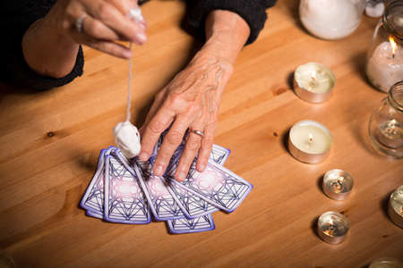 Old fortune teller is choosing a card for her client