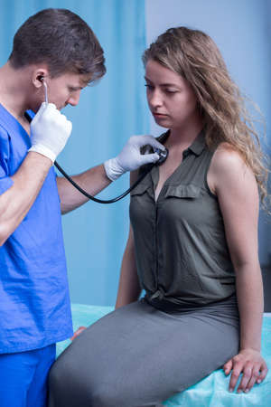 Doctor with stethoscope examining ill female patientの写真素材