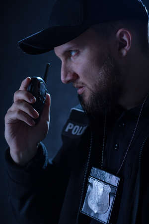 Portrait of angry policeman using walkie talkieの写真素材