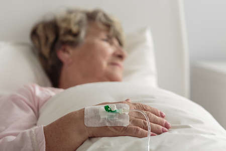 Ill female retiree lying in hospital bed