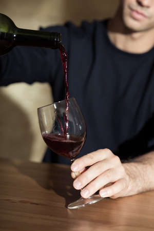 Man holding glass and pouring red wineの写真素材