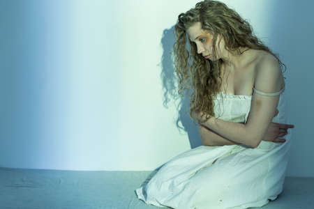 Image of hopeless rape victim in trauma sitting on floor