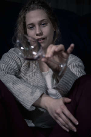 Young drunk alcoholic woman holding empty glassの写真素材