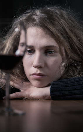 Sad young woman drinking red wine aloneの写真素材
