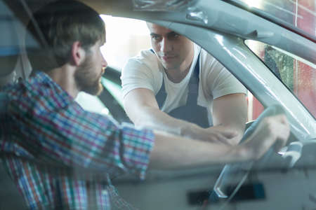 Photo of handsome worker of automotive repair shop with clientの写真素材