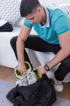 Young man packing gym bag before trainingの写真素材