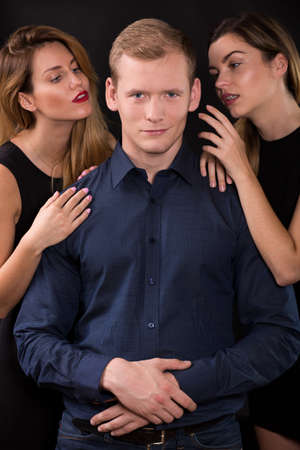 Love triangle - seductive women tempting handsome manの写真素材