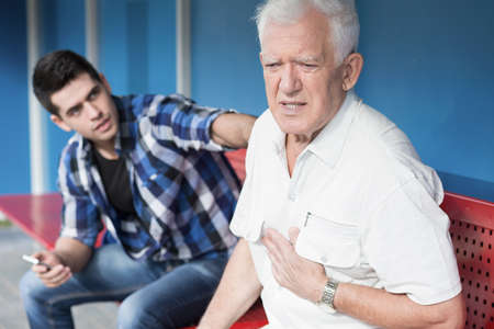 Retiree with chest pain and helpful young manの写真素材