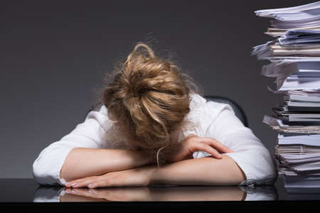Image of overworked woman sleeping on desk at her workplaceの写真素材