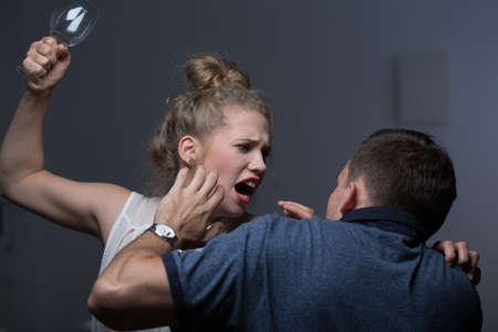 Violent wife hitting husband with glass bottleの写真素材