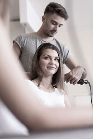Hairdresser is doing young woman's hairの写真素材