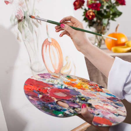 Young talented woman painting a nature on white canvasの写真素材