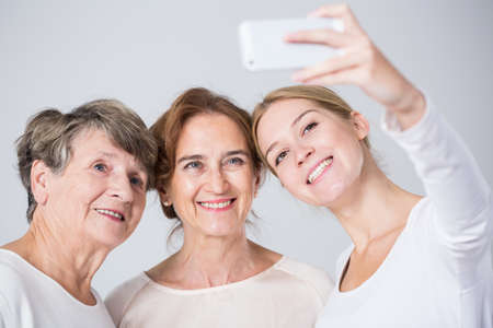 Smiling granddaughter taking perfect family selfie - horizontal viewの写真素材