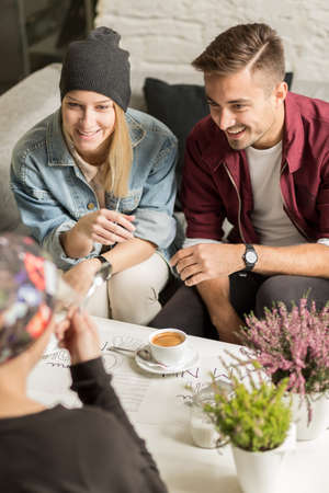 Three happy friends on meeting in cafeの写真素材
