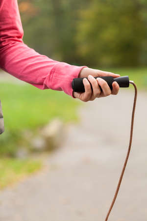 Close-up on a jumping rope in hand of a young womanの写真素材