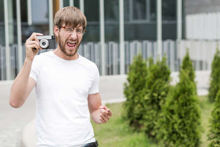 Happy young man holding camera and pointingの写真素材