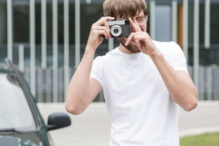 Young man in white shirt is taking photoの写真素材