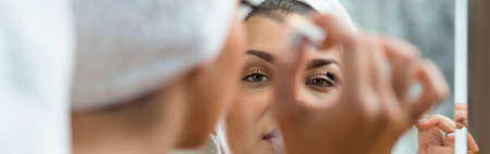 Panorama of a smiling woman applying mascara on her eyelashesの写真素材