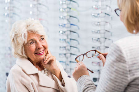 Young optician selling glasses in optical shopの写真素材