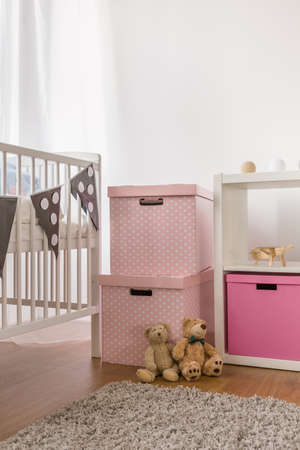 Photo of white cot and pink boxes in child bedroom