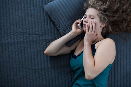 Picture of sleepy female in nightgown talking on phone