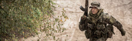 Young soldier running up th hill with rifle