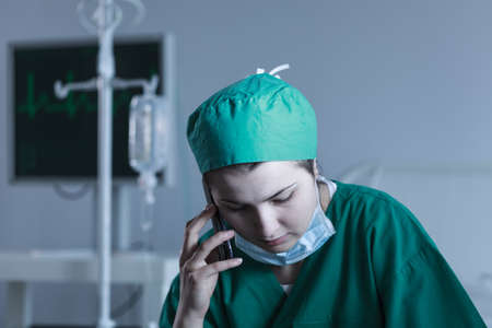 Picture of female doctor wearing sterile uniform talking on phoneの写真素材