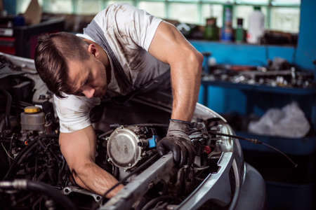Picture showing muscular car service worker repairing vehicle