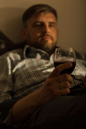 Image of bored lonely guy with glass of wineの写真素材