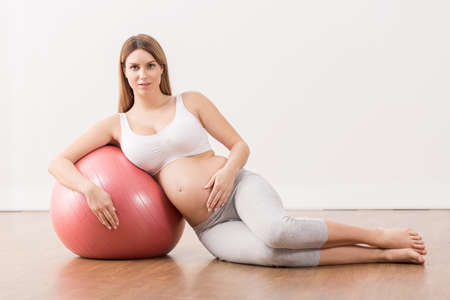 Pregnant woman exercising at home with fitness ball