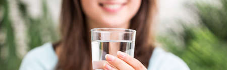 Panoramic photo of woman holding the glass of water