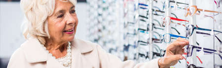 Smiling senior woman in trendy optical storeの写真素材