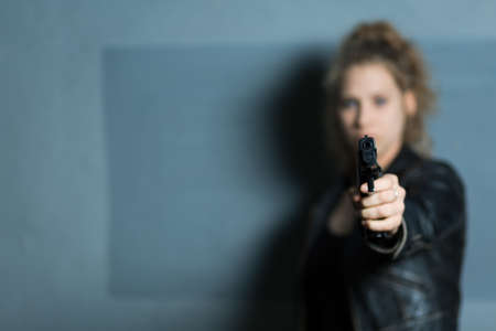 Female murderer with gun aiming at someoneの写真素材