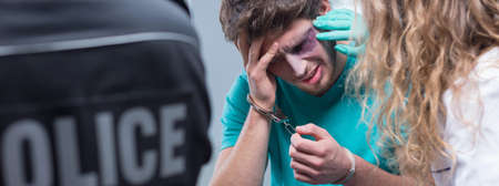 Handcuff bruised man in emergency room with policeの写真素材