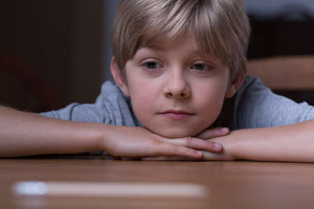 Cute blonde boy lying on the tableの写真素材