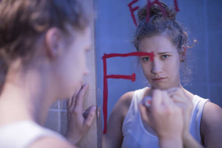 Crying girl is looking in the mirror