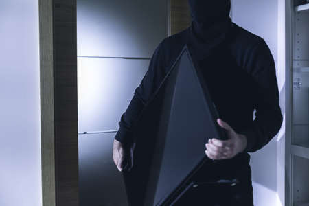 Close up of thief holding modern expensive televisionの写真素材