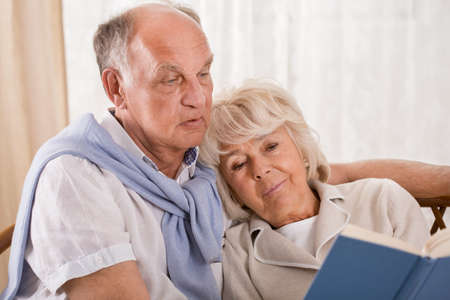 Elegant senior couple reading a book together