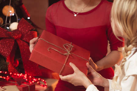 Image of mother giving red christmas gift to child