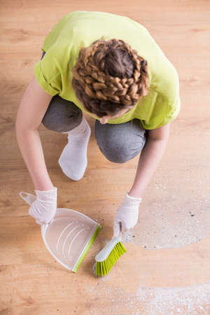 Photo of woman with gloves and dustpan during houseworkの写真素材