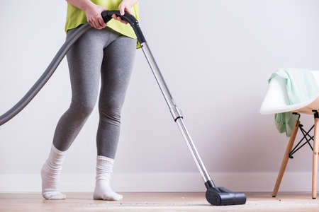 Image of woman dusting dirty apartment with vacuumの写真素材