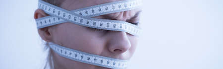 Female head wrapped in measuring tape - panoramaの写真素材