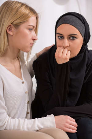 Young blonde european girl supporting arab womanの写真素材