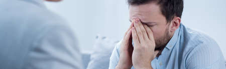 Close-up of worried young man on psychotherapy sessionの写真素材